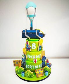 3 tiered Fortnite birthday cake with green frosting, edible battle bus and cake toppers