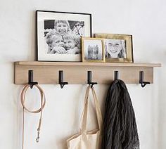 a couple of pictures hanging on a wall next to a coat rack with two purses