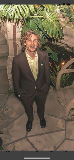 a man in a suit and tie standing next to some stairs with palm trees behind him