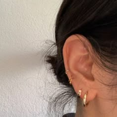 a close up of a person's ear with two gold hoop earrings on it