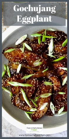 a plate filled with meat covered in sesame seeds and garnished with green onions