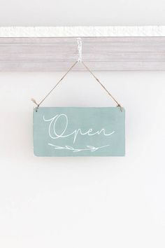 an open sign hanging on a white wall