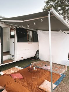 a camper van with its door open and covered in brown tarp next to it