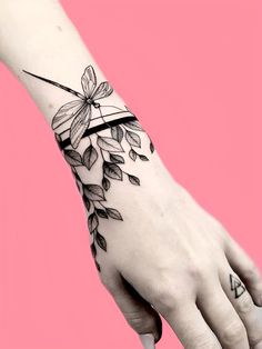 a woman's hand with a flower tattoo on the left side of her arm