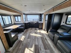 the interior of an rv with couches, tables and kitchen area in front of windows