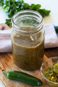 a glass jar filled with pickles next to a bowl of chopped green peppers on a cutting board