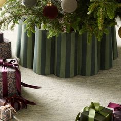 presents under a christmas tree with ornaments and ribbons on the floor next to it,