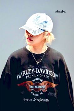 a woman wearing a harley davidson t - shirt and hat with her hair pulled back