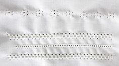 three pieces of white fabric with black dots on the edges and two rows of holes in the middle