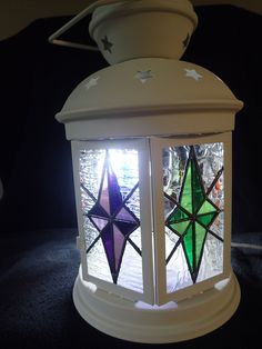 a white lantern with stained glass stars on it