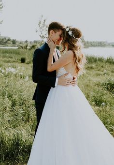 a bride and groom kissing in the grass