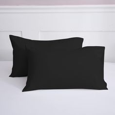 two black pillows sitting on top of a white bed