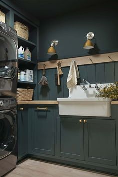 a washer and dryer in a kitchen with green painted cabinets, wood flooring and open shelving