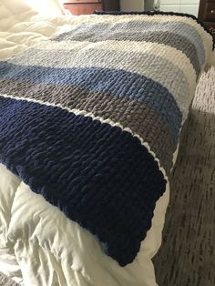 a bed with a blue and gray blanket on top of it