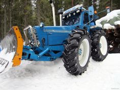 a blue tractor is plowing the snow with it's skis on top