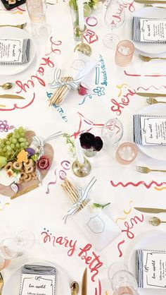 the table is set with wine glasses, plates and napkins that say happy birthday