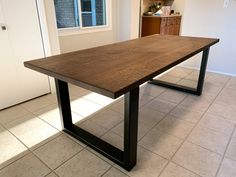 a large wooden table sitting on top of a tiled floor next to a kitchen counter