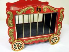 a small red and gold toy cart with wheels on it's sides, in front of a white background