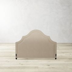 an upholstered headboard on a wooden floor in front of a white wall