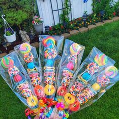 a bunch of candy sticks are in a vase on the grass with flowers and potted plants behind them