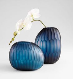 two blue vases sitting next to each other with a white flower in the middle