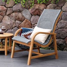 two chairs and a table on a patio with stone wall in the backround