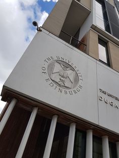 the university of dublin building is white and has columns on each side, with an emblem above it