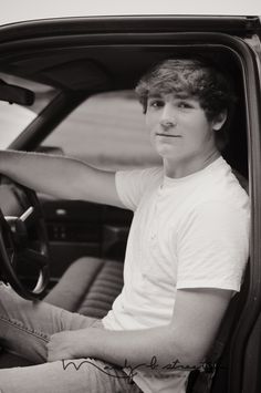 a young man sitting in the driver's seat of a car