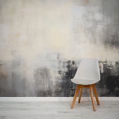 a white chair sitting in front of a wall with grey and black paint on it