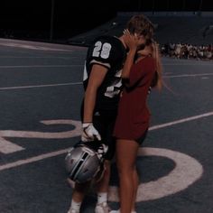 a man and woman kissing on the football field