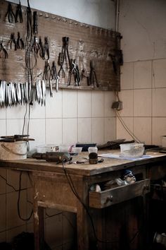 an old workbench with lots of tools hanging on the wall and some wires attached to it