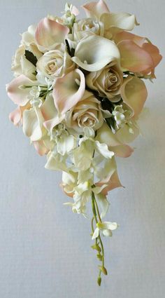 a bridal bouquet with white and pink flowers on the stems, in front of a plain background