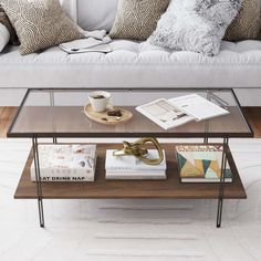 a coffee table with some books on it in front of a white couch and pillows