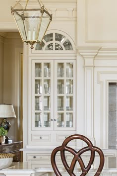 an elegant dining room with white cabinets and marble counter tops, glass fronted china cabinet