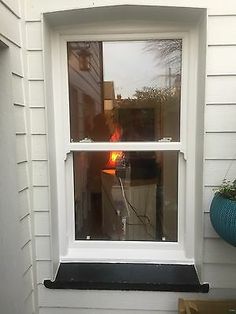 a white window sitting on the side of a house next to a potted plant