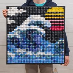 a man holding up a large piece of art made out of legos