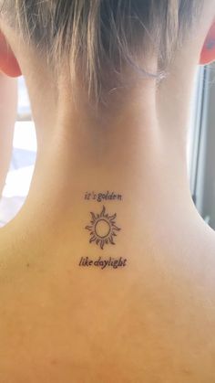 the back of a woman's neck with a tattoo saying it is golden like daylight