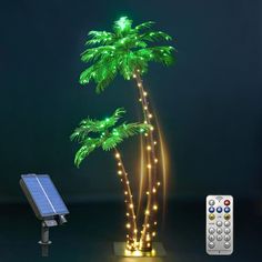 a solar powered palm tree next to a remote control on a dark background with lights