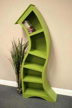 a green curved shelf next to a potted plant and a wall mounted bookcase