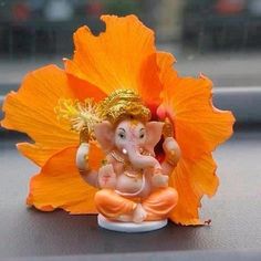 an orange flower sitting on top of a table next to a statue of ganesh