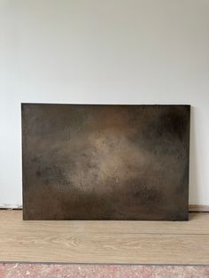 a large metal piece sitting on top of a hard wood floor next to a white wall