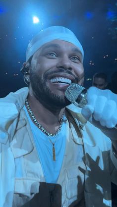 a man with a microphone in his hand and wearing a turban on top of his head