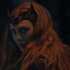 a woman with long red hair and horns on her head is staring at the camera