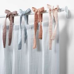 four different colored bows hanging from the side of a curtain