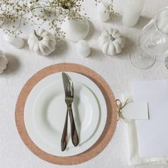 the place setting is set with silverware and napkins, along with white pumpkins