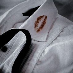 a close up of a white shirt with a black tie and red lipstick on it