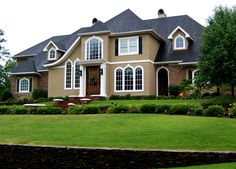 a large house with lots of windows on the front and side of it, surrounded by lush green grass