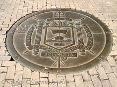 a manhole cover with the seal of an emblem on it in brick pavers