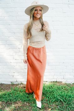 Product Details: Experience sophistication and comfort with our All Dressed Up Maxi Skirt. The lightweight, textured material in a rust color exudes elegance, while the elastic waistband provides a versatile and comfortable fit. Complete your wardrobe with this classy and timeless maxi skirt. Product Material: 100% Polyester Hope's Go-To Outfit: "I paired this amazing skirt with our Layer It Up Lace Top in champagne, my favorite pair of boots, and my go-to western hat for the cutest concert fit! Satin Skirt With Cowboy Boots, Burnt Orange Skirt Outfit, Orange Maxi Skirt Outfit, Fall Skirt Outfits With Boots, Orange Skirt Outfit, Skirt Outfits With Boots, Womens Western Fashion, Cute Western Outfits, Skirt Outfit Fall