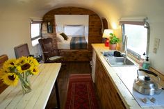 a kitchen and dining area inside an rv with sunflowers in the foreground